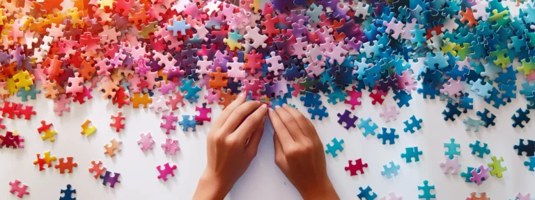 a person meticulously arranging colorful puzzle pieces in a perfectly symmetrical pattern on a white table.